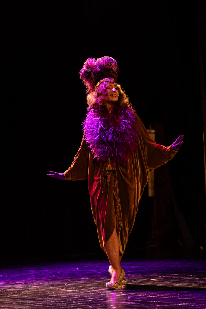 Danseuse burlesque sur scène habillée d'un manteau style années 30.