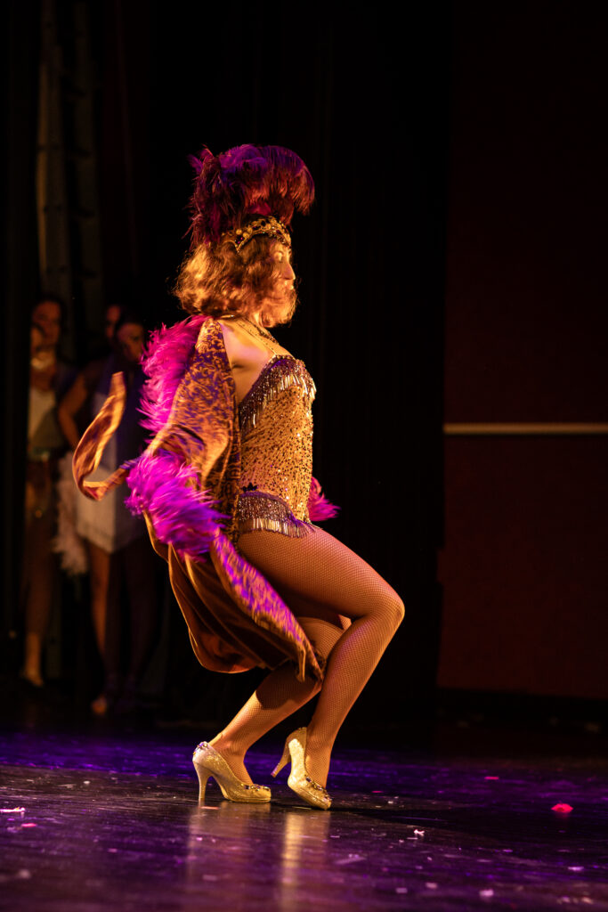 Danseuse burlesque sur scène retirant son manteau